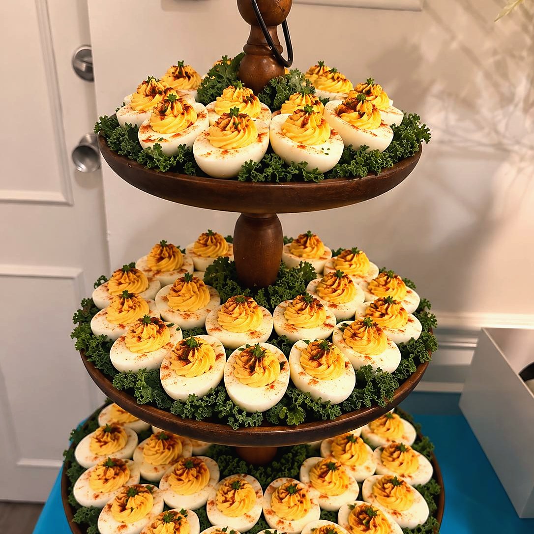 Three-tier wooden stand of deviled eggs on beds of curly kale